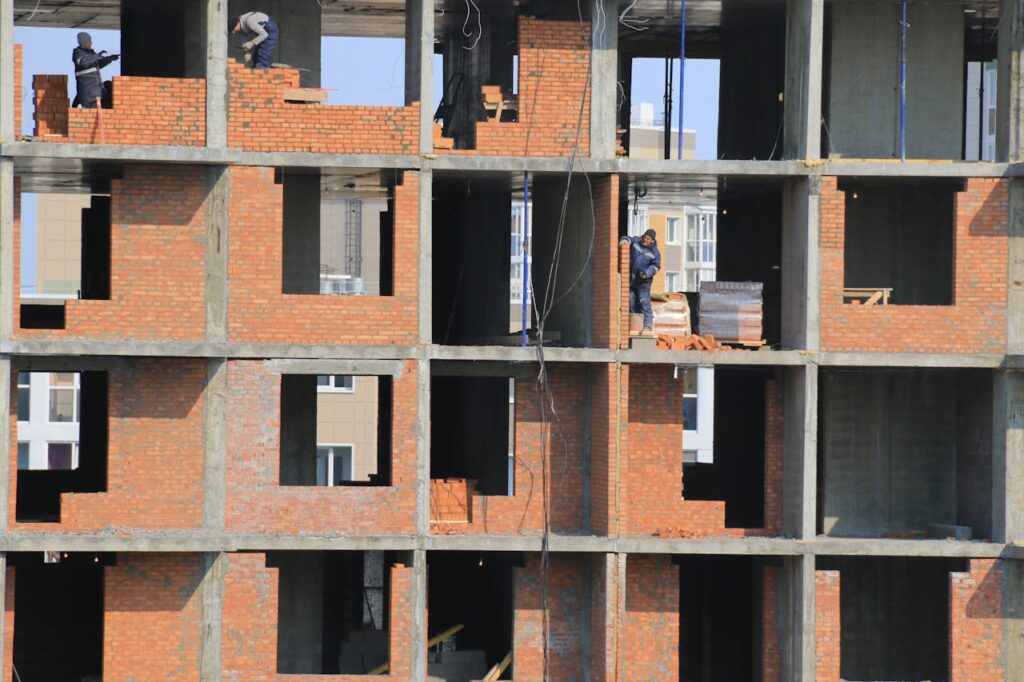 View of construction workers building brick walls on an unfinished urban apartment.