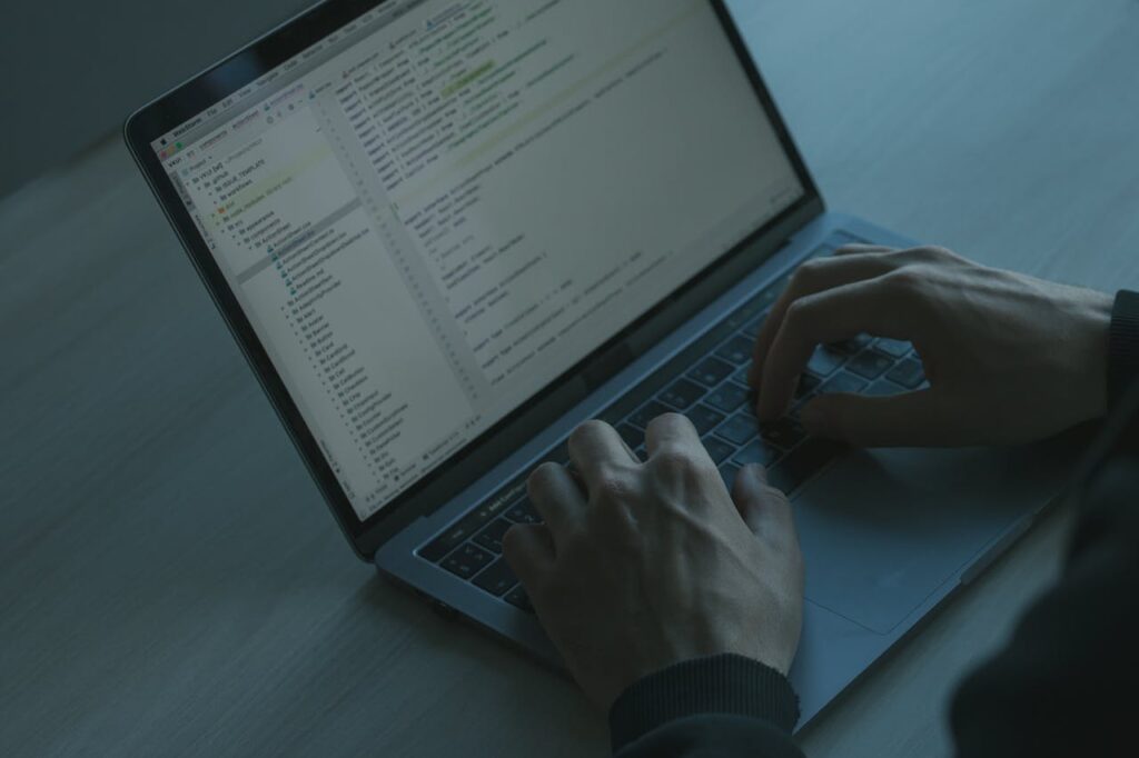 A person typing code on a laptop with a focus on cybersecurity and software development.